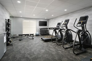 A gym with treadmills, a bench, dumbbells, and a TV on the wall. - Fairfield Inn & Suites by Marriott Auburn Opelika (Opelika)
