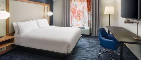 A hotel room with a bed, desk, chair, TV, and curtains.
