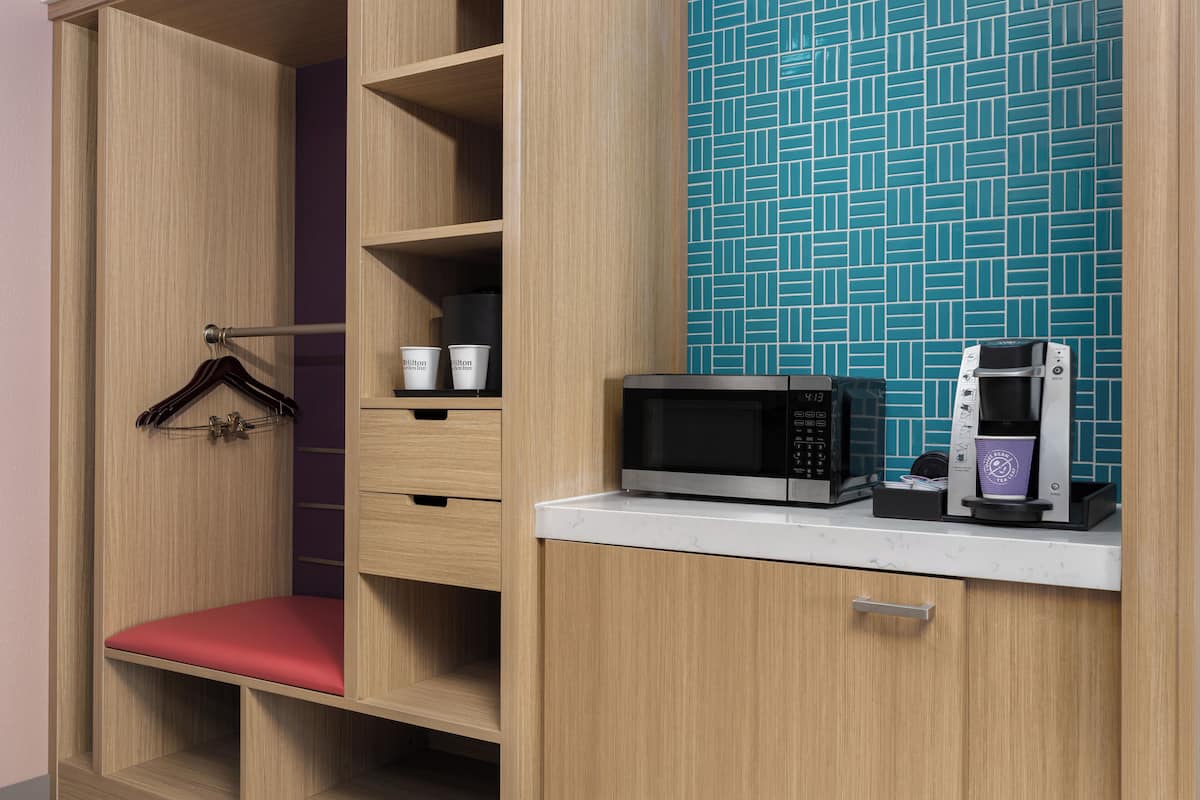 A kitchenette with a microwave, coffee maker, and storage cabinets.