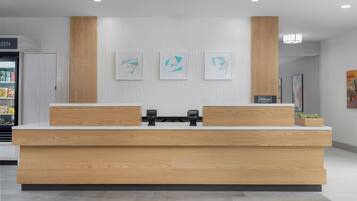 Een houten receptiebalie in een hotel, met een digitaal scherm en een bordje met de tekst 'Hilton Honors'.