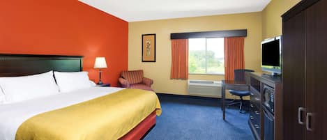 A hotel room with a bed, a desk, a chair, a television, and a wardrobe.