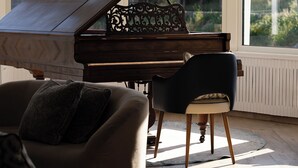 A grand piano in a room with large windows, a modern chandelier, and a comfortable seating area. - La Marine (Barneville-Carteret)