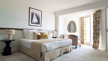 A neatly arranged bedroom with a bed, bedside tables, a chair, a mirror, and a door with curtains.