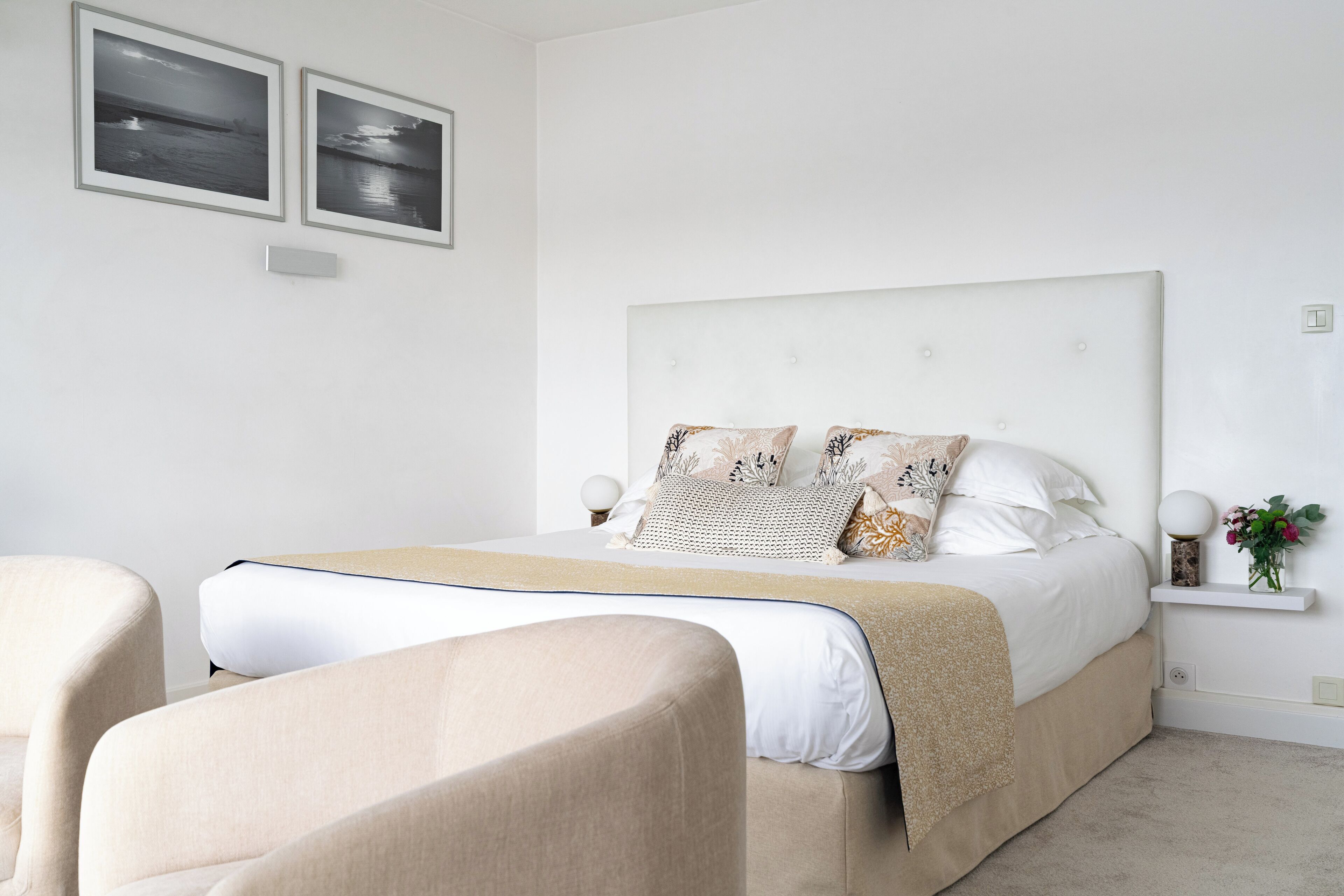 A bedroom with a large bed, two bedside tables, a nightstand, and a chair.