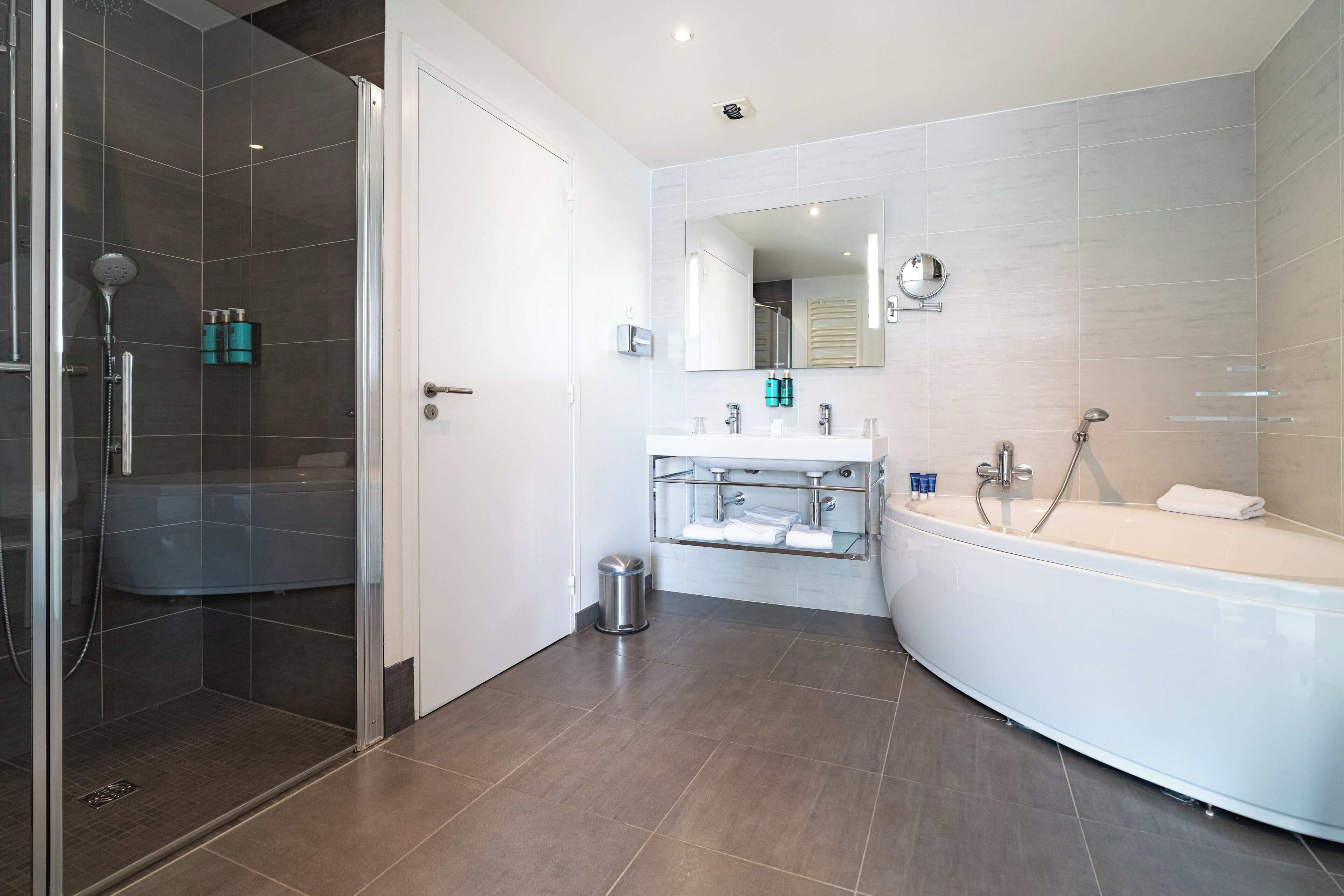 A modern bathroom with a glass-enclosed shower, a freestanding bathtub, and a vanity with a mirror.