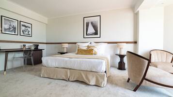Ein ordentlich eingerichtetes Hotelzimmer mit Bett, Schreibtisch, Stuhl und gerahmten Bildern an der Wand.