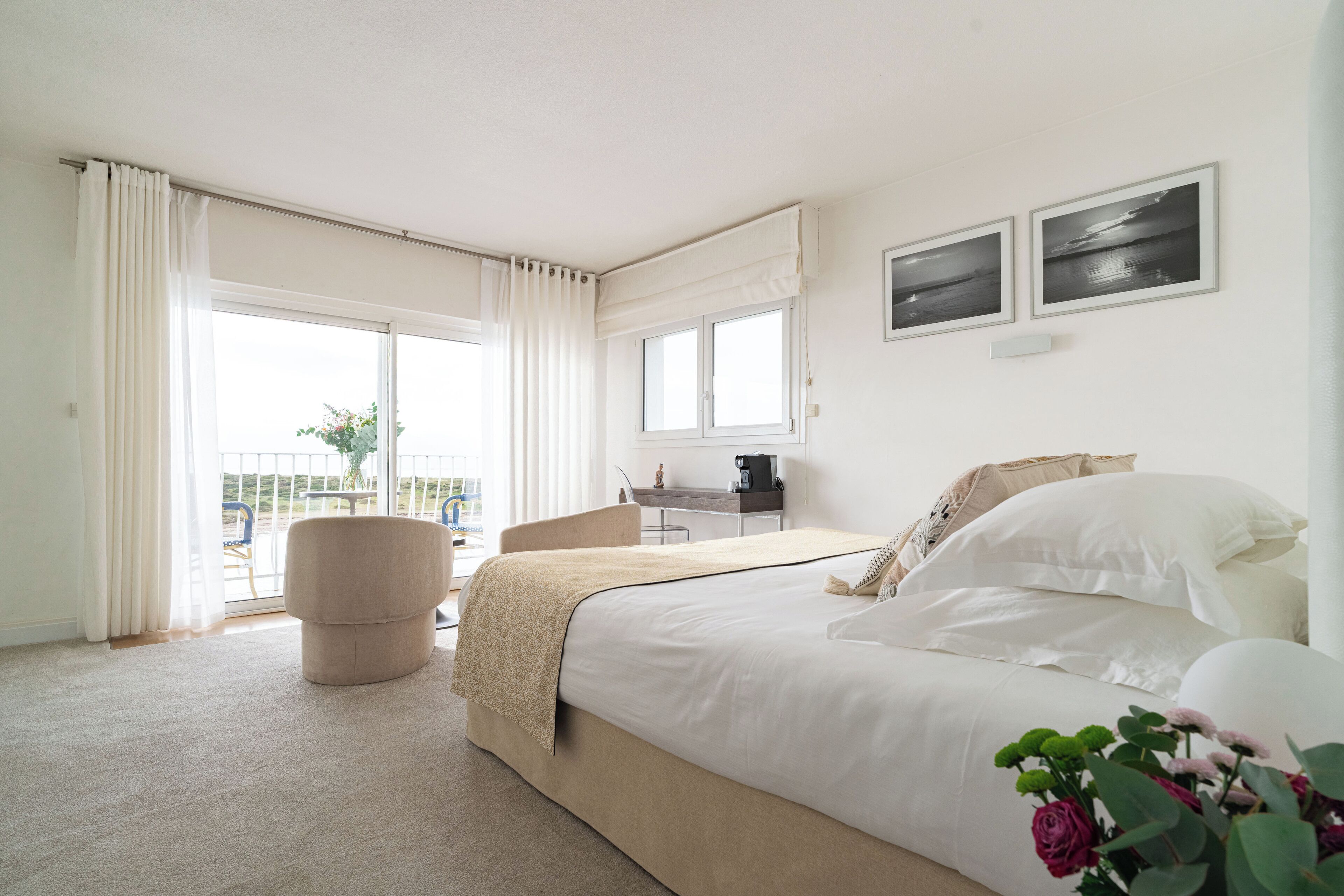 Een hotelkamer met een bed, een stoel, een bureau en uitzicht op het groen.
