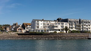A waterfront hotel with multiple balconies, a stone wall, and a clear blue sky.