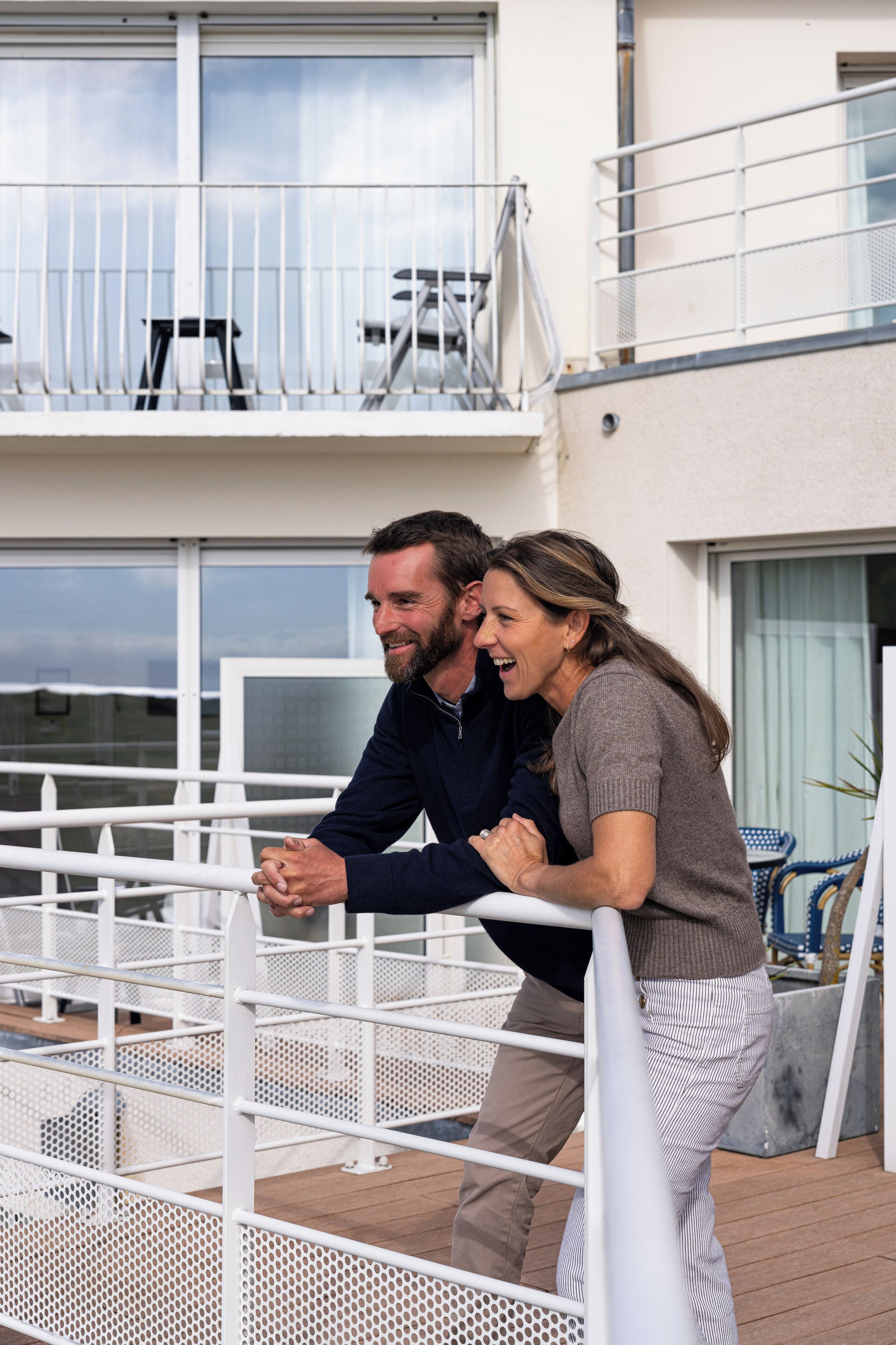 A balcony with white railings and a view of the sea.