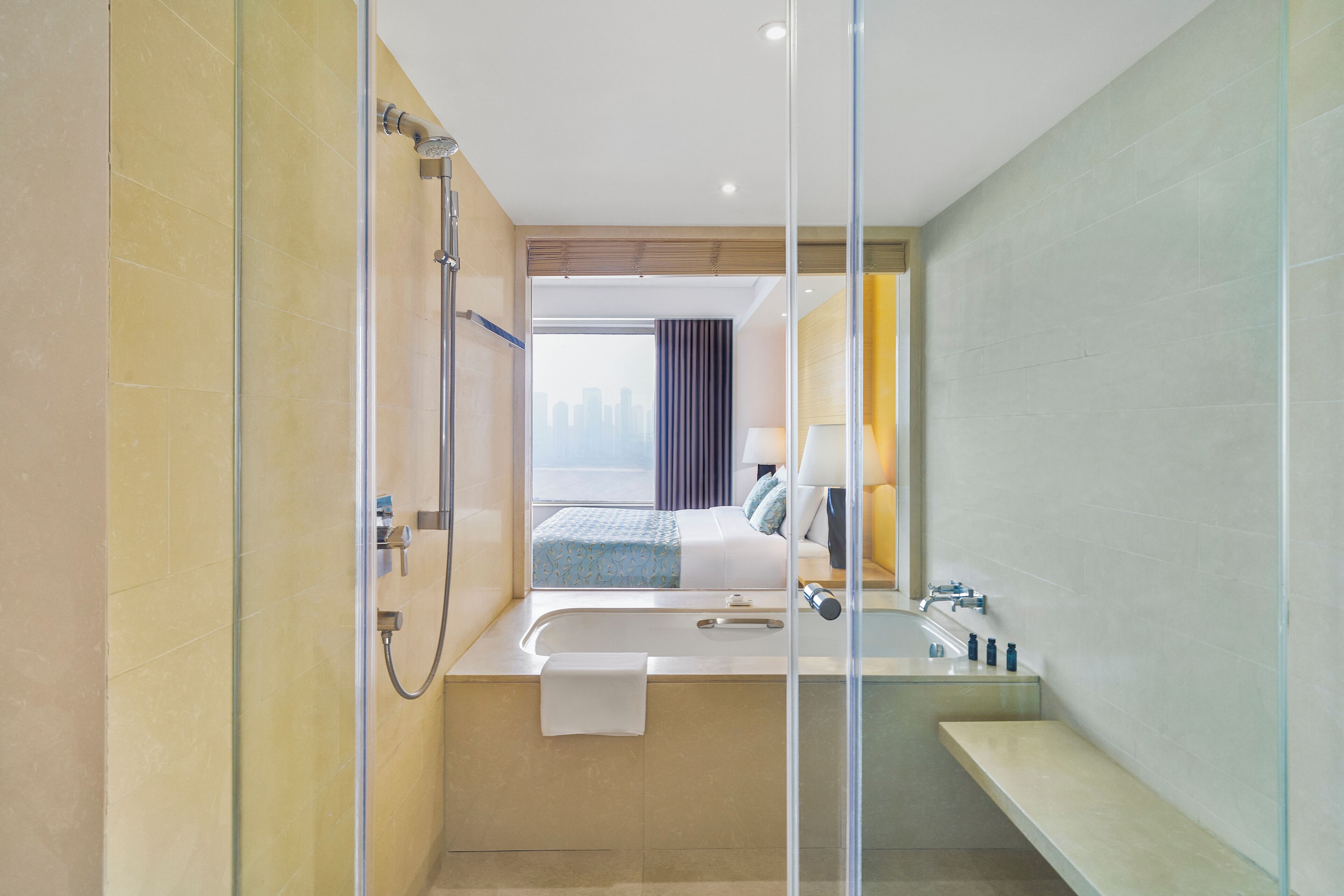 A modern hotel bathroom with a glass shower enclosure, a bathtub, and a sink.