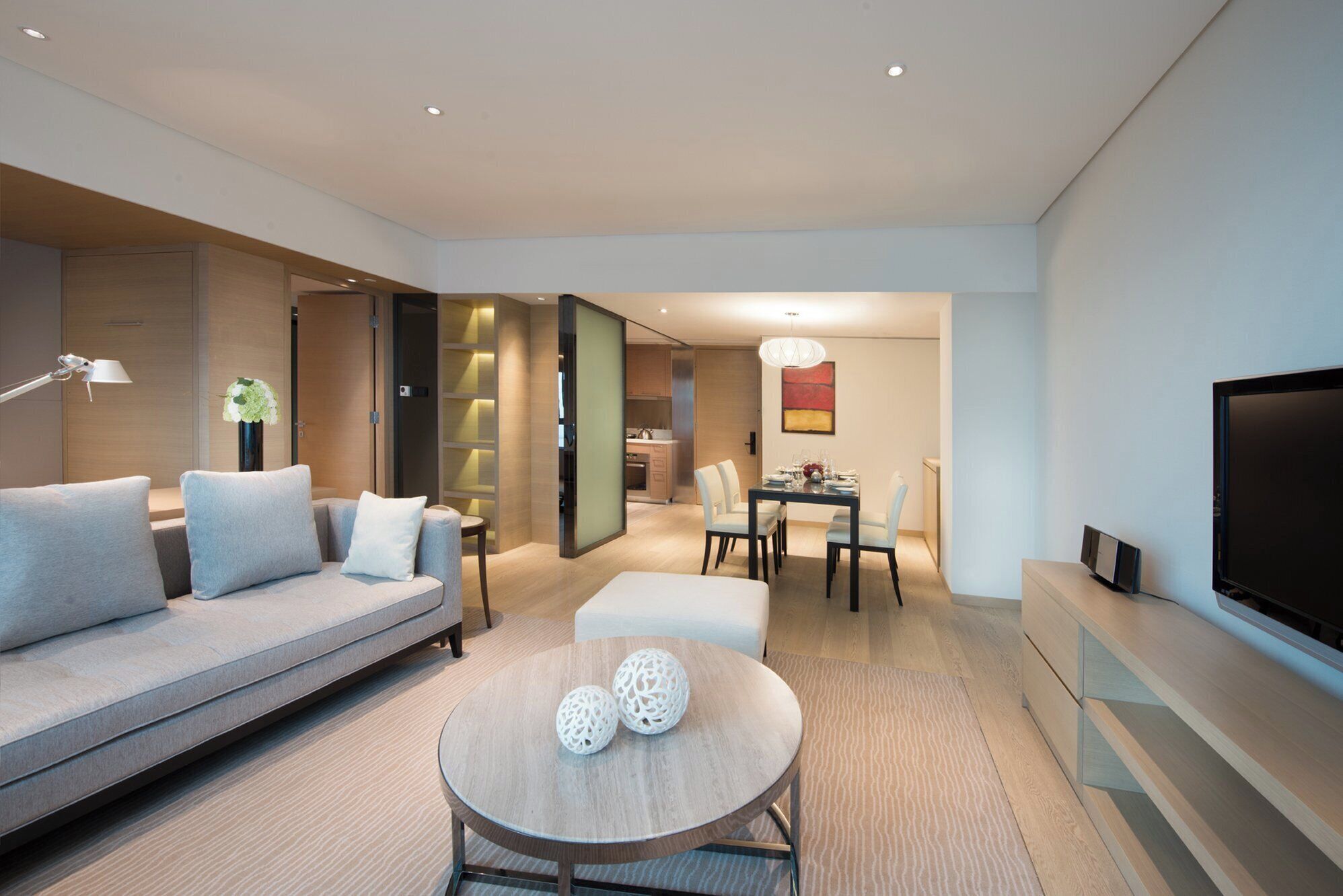 A modern living room with a sofa, a dining table, and a TV.