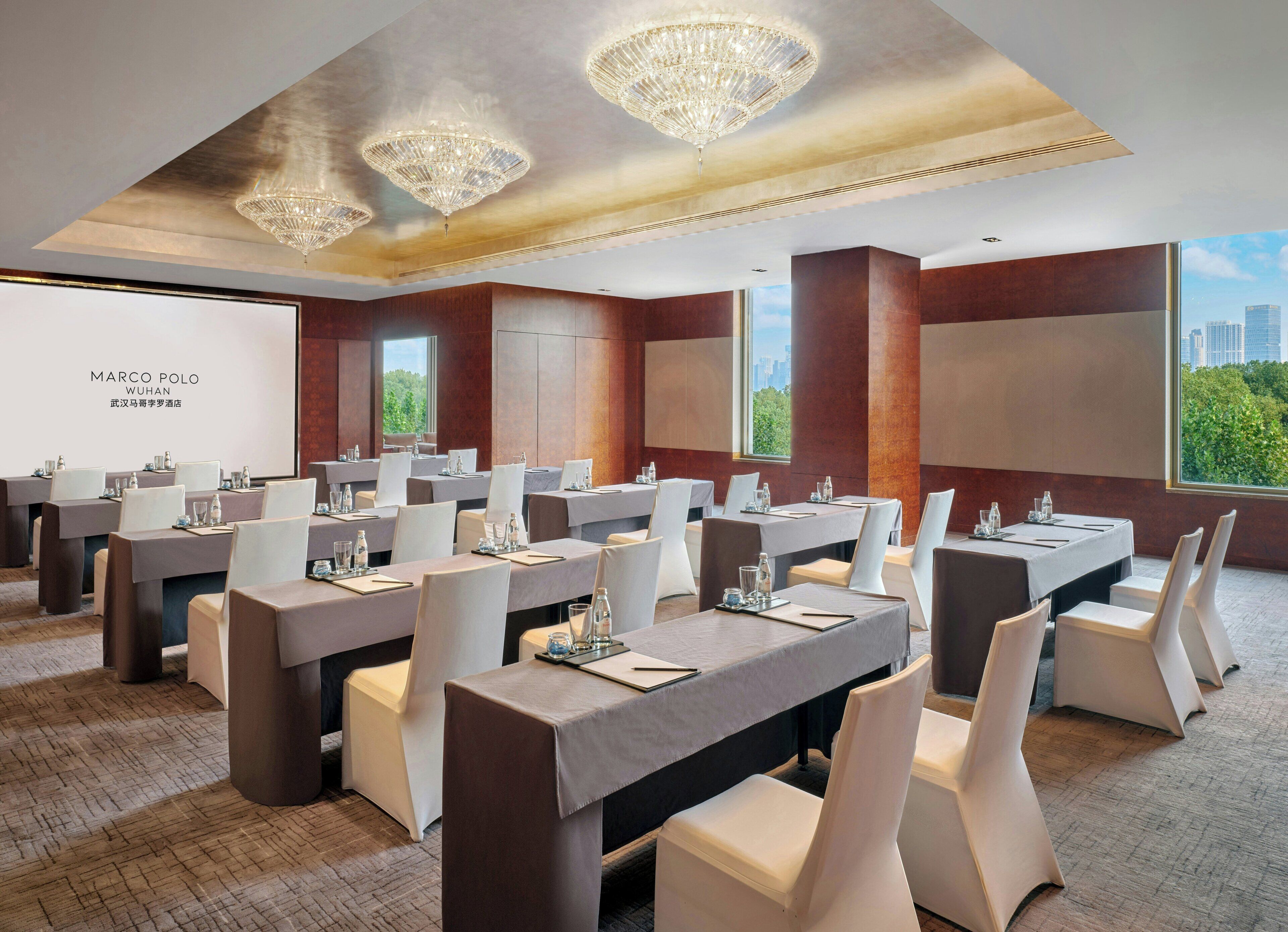 A conference room with tables, chairs, and a projector screen.