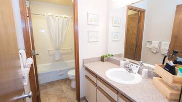 A bathroom with a bathtub, toilet, sink, and mirror.