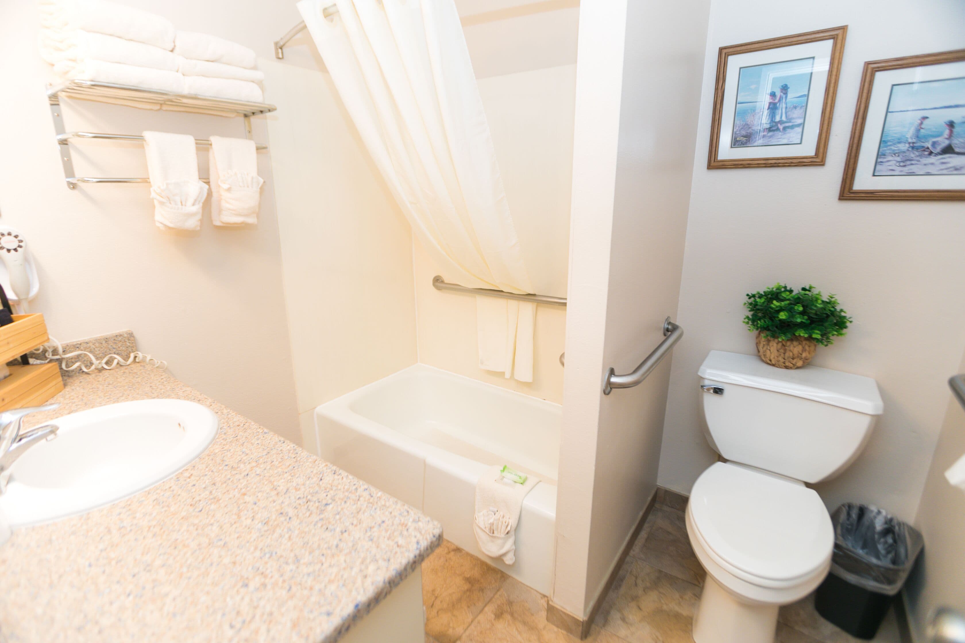 A bathroom with a sink, bathtub, toilet, and towel rack.