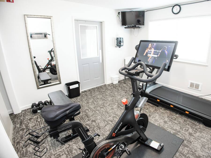 A home gym with an exercise bike, treadmill, and weights.