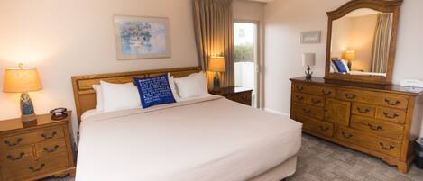 A hotel room with a large bed, wooden nightstands, a dresser, and a mirror.