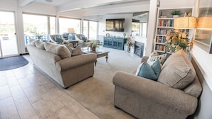 A spacious living room with a large sofa, a coffee table, and a bookshelf.