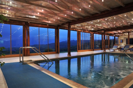 Una piscina techada, una piscina al aire libre, sombrillas