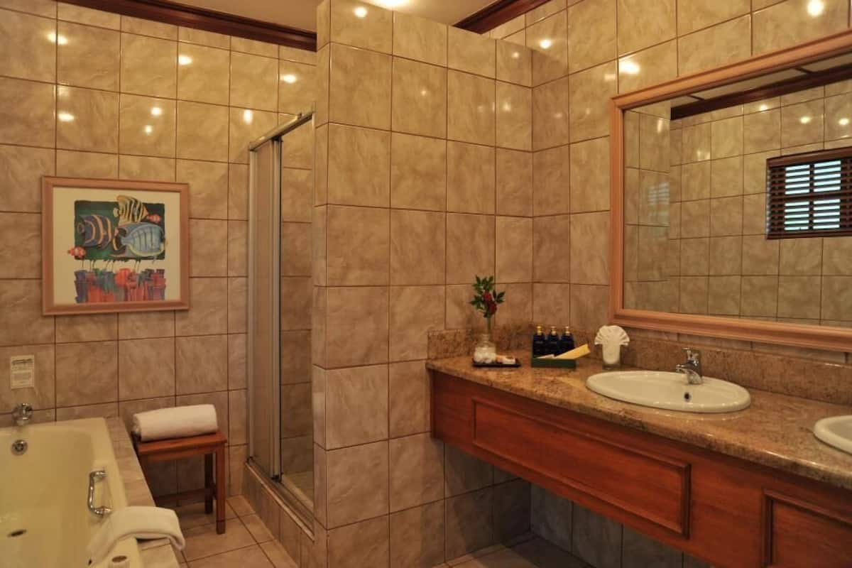 Ein Badezimmer mit einem großen Spiegel, einem Waschbecken, einer Dusche und einem gerahmten Bild an der Wand.
