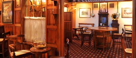 A traditional pub interior with wooden furniture, a patterned floor, and various decorations including a globe and framed pictures.