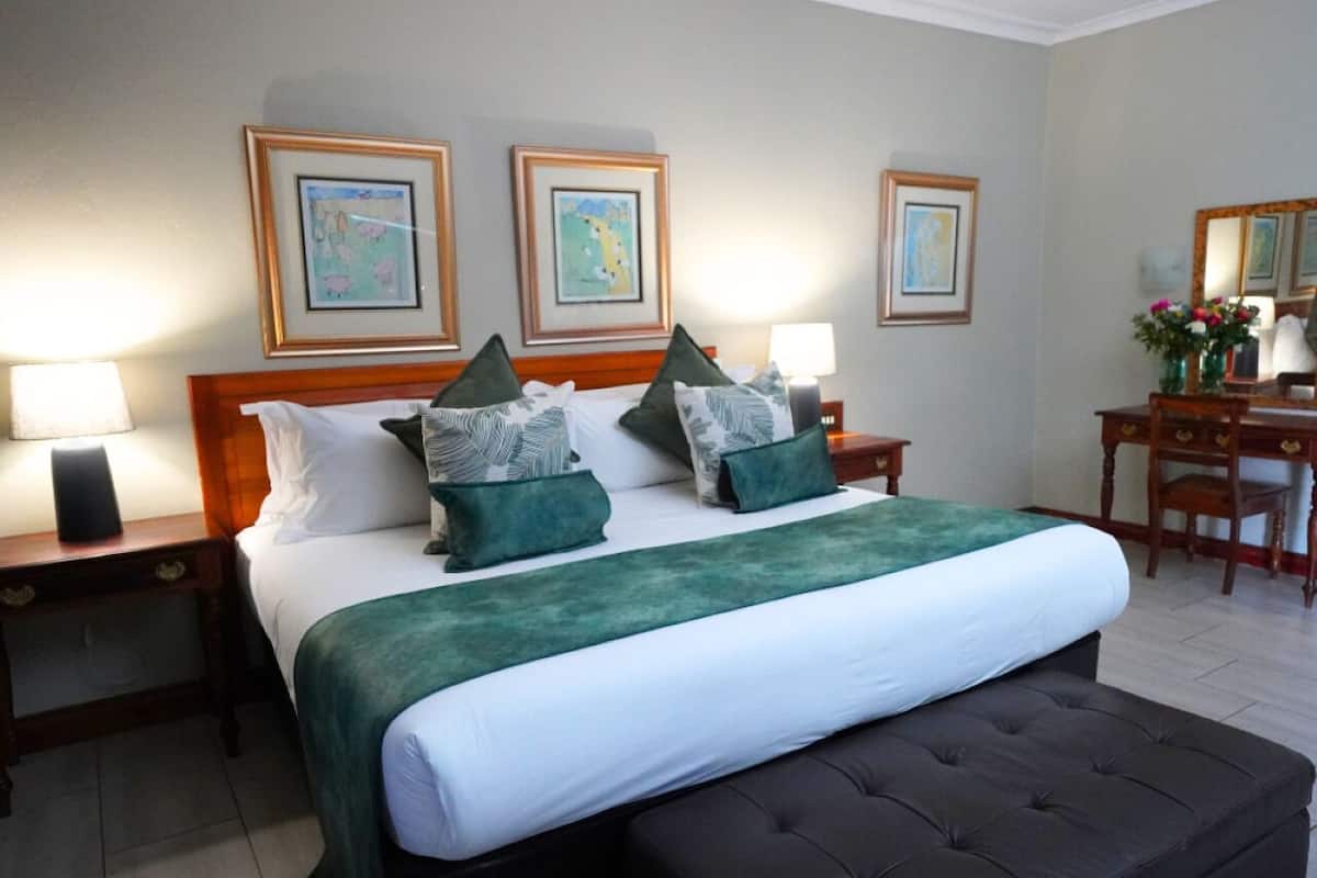 Ein ordentlich eingerichtetes Hotelzimmer mit einem großen Bett, zwei Nachttischen und gerahmten Bildern an den Wänden.