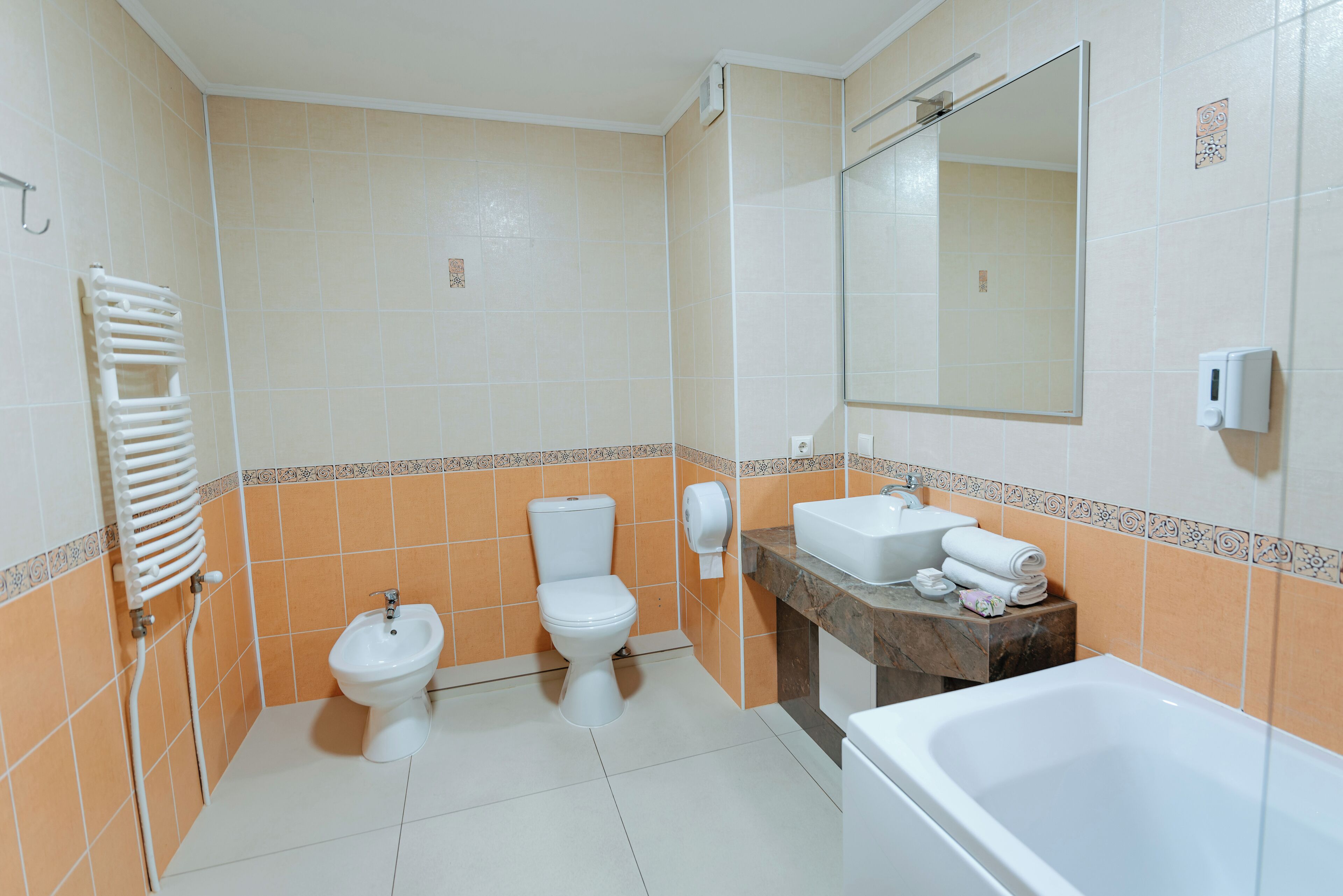 Un baño con dos inodoros, un bidé, un lavabo, un espejo y una bañera.