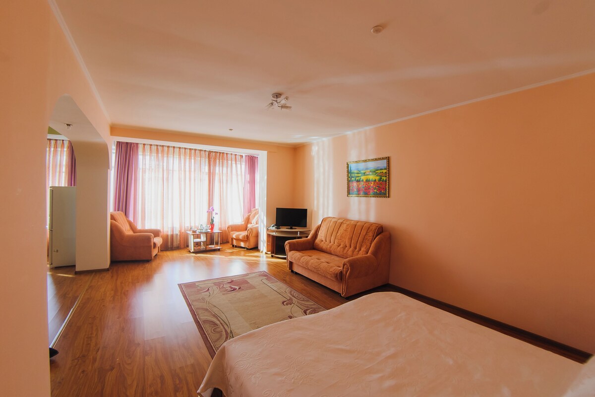 A hotel room with a bed, a sofa, a TV, and a desk.