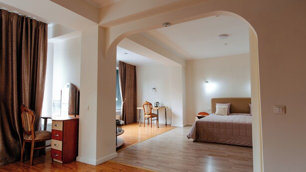 Een hotelkamer met een houten vloer, een bed, een bureau met stoel en een kast.