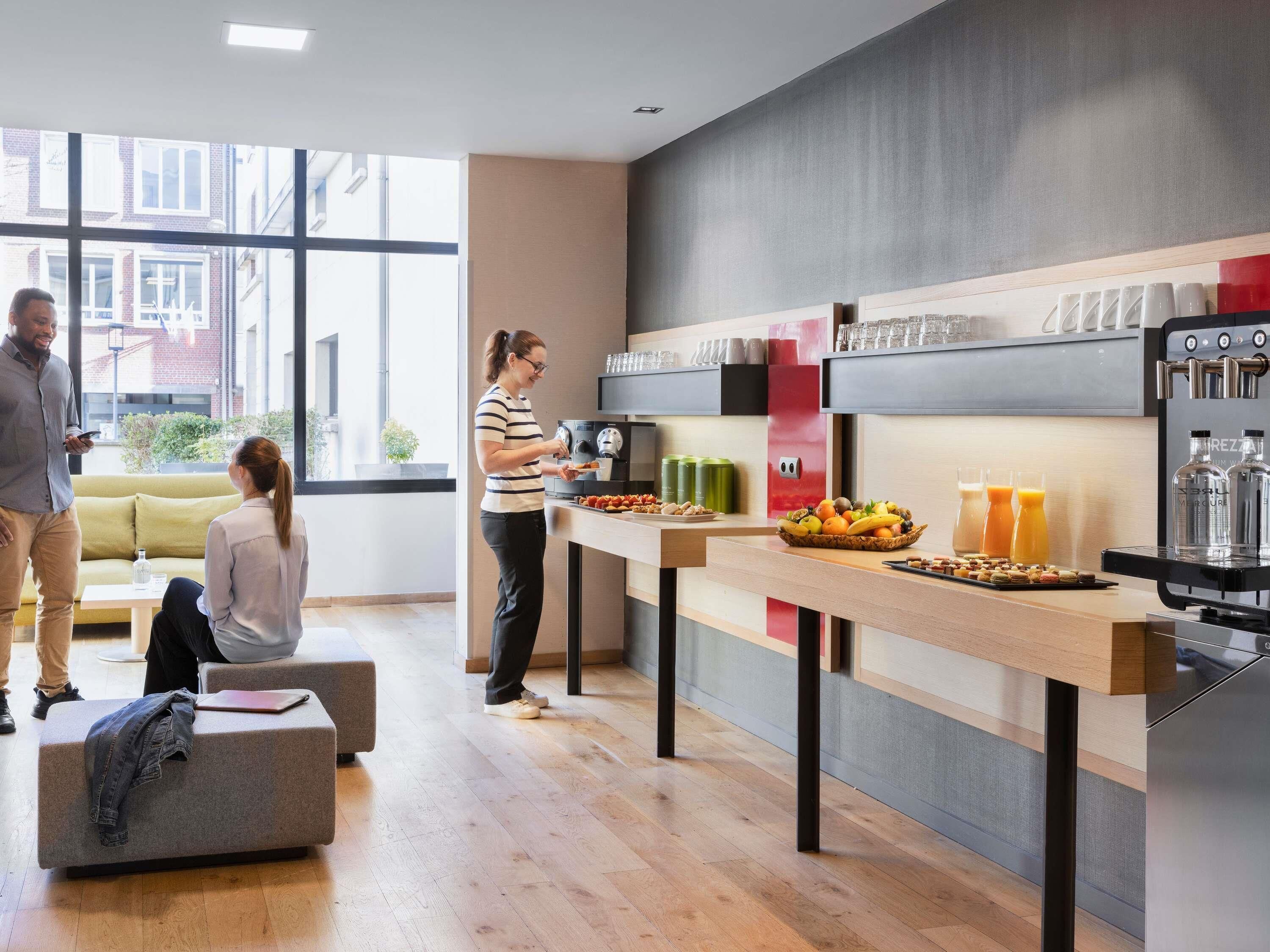A modern kitchen with a coffee machine, fruit bowl, and a seating area with a sofa and table.
