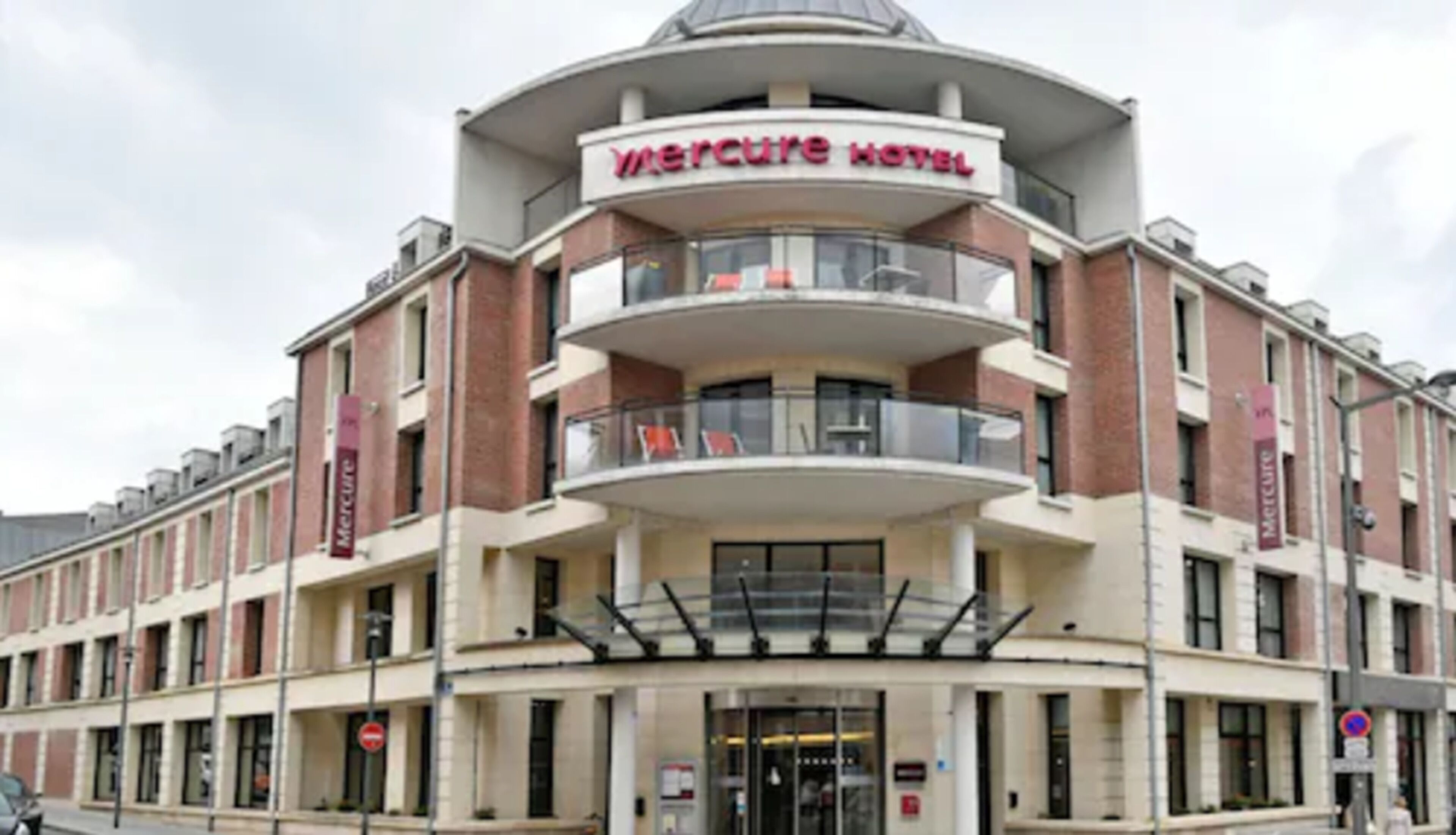 A multi-story hotel with a prominent 'Mercure Hotel' sign. It features a central atrium with balconies, and the facade includes multiple windows and a symmetrical design.