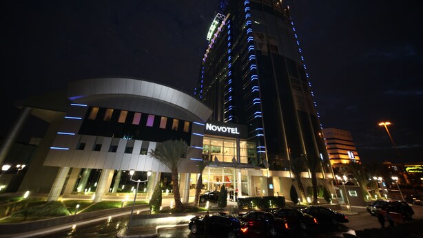 Een Novotel hotel met een modern ontwerp, met een opvallende, gebogen gevel en verlichte signage.