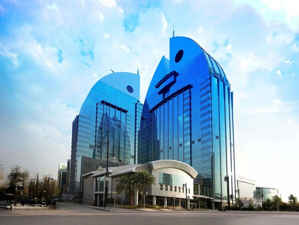 A modern hotel with a curved facade and a prominent logo.