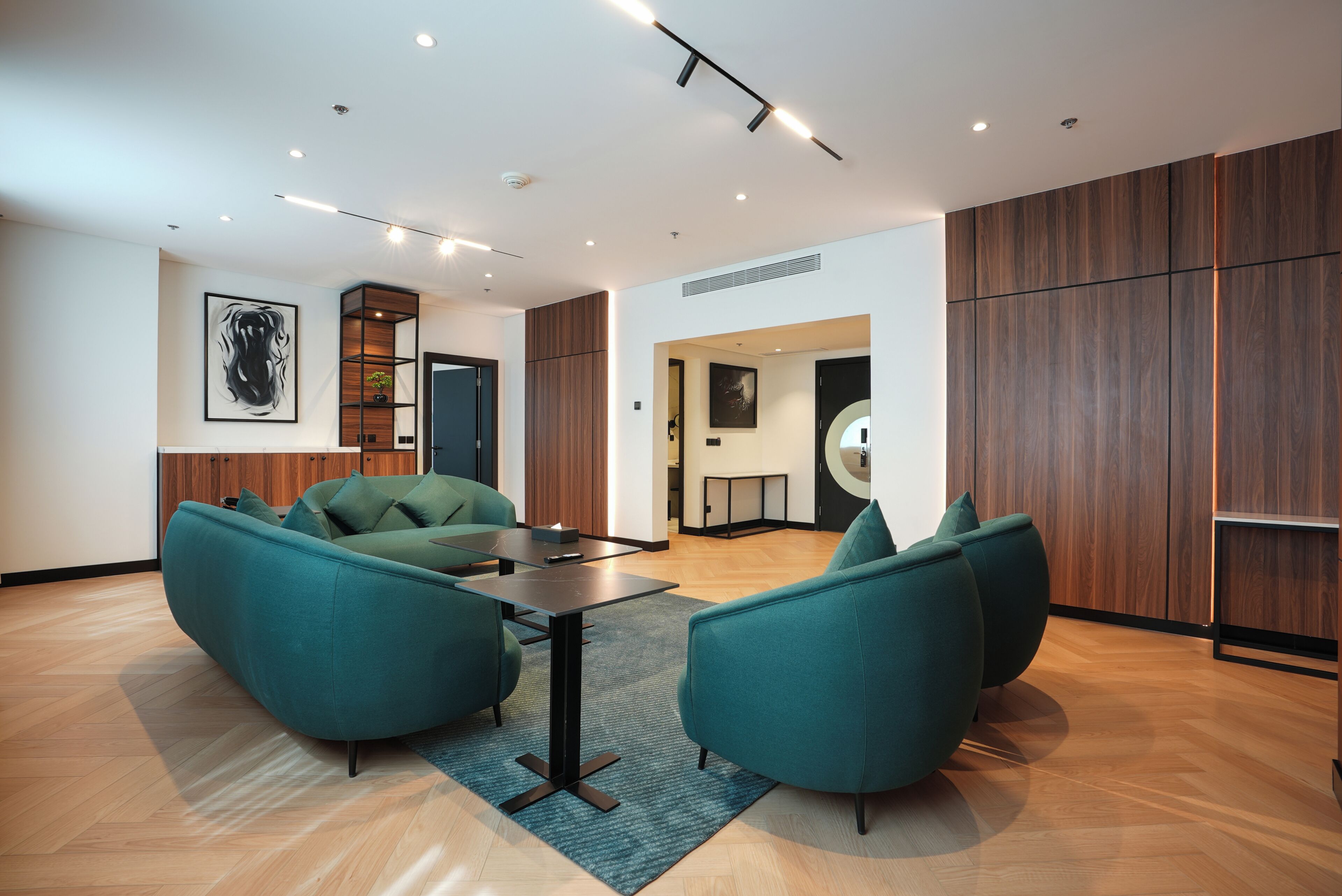 A modern interior with teal sofas, a wooden floor, and recessed lighting.