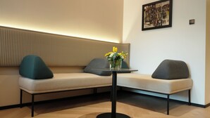 A modern seating area with a sofa and a small table, a vase with flowers, and a framed artwork on the wall. - Novotel Riyadh Al Anoud (Riyadh)