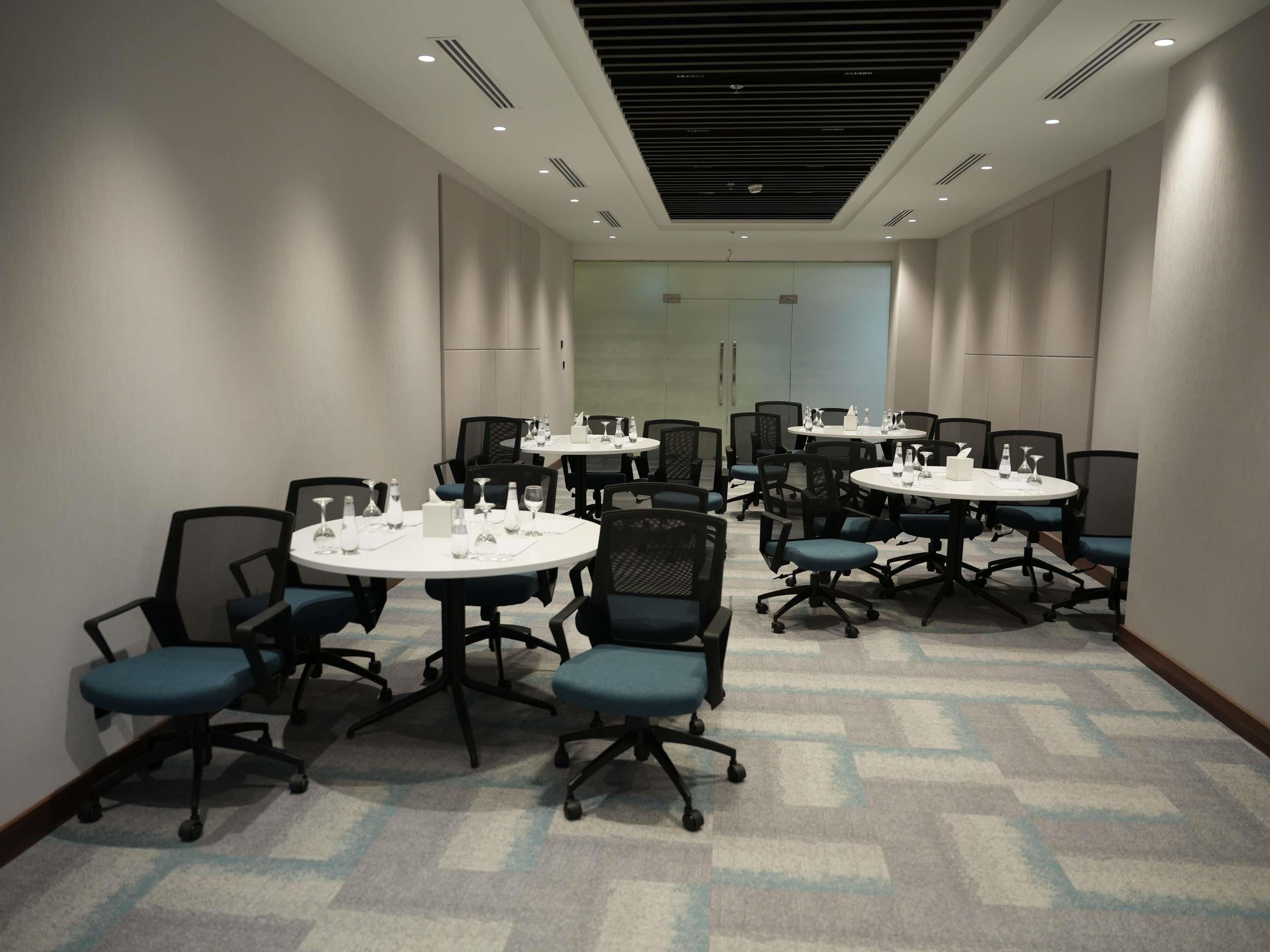 A conference room with multiple tables and chairs, equipped with water bottles and glasses.