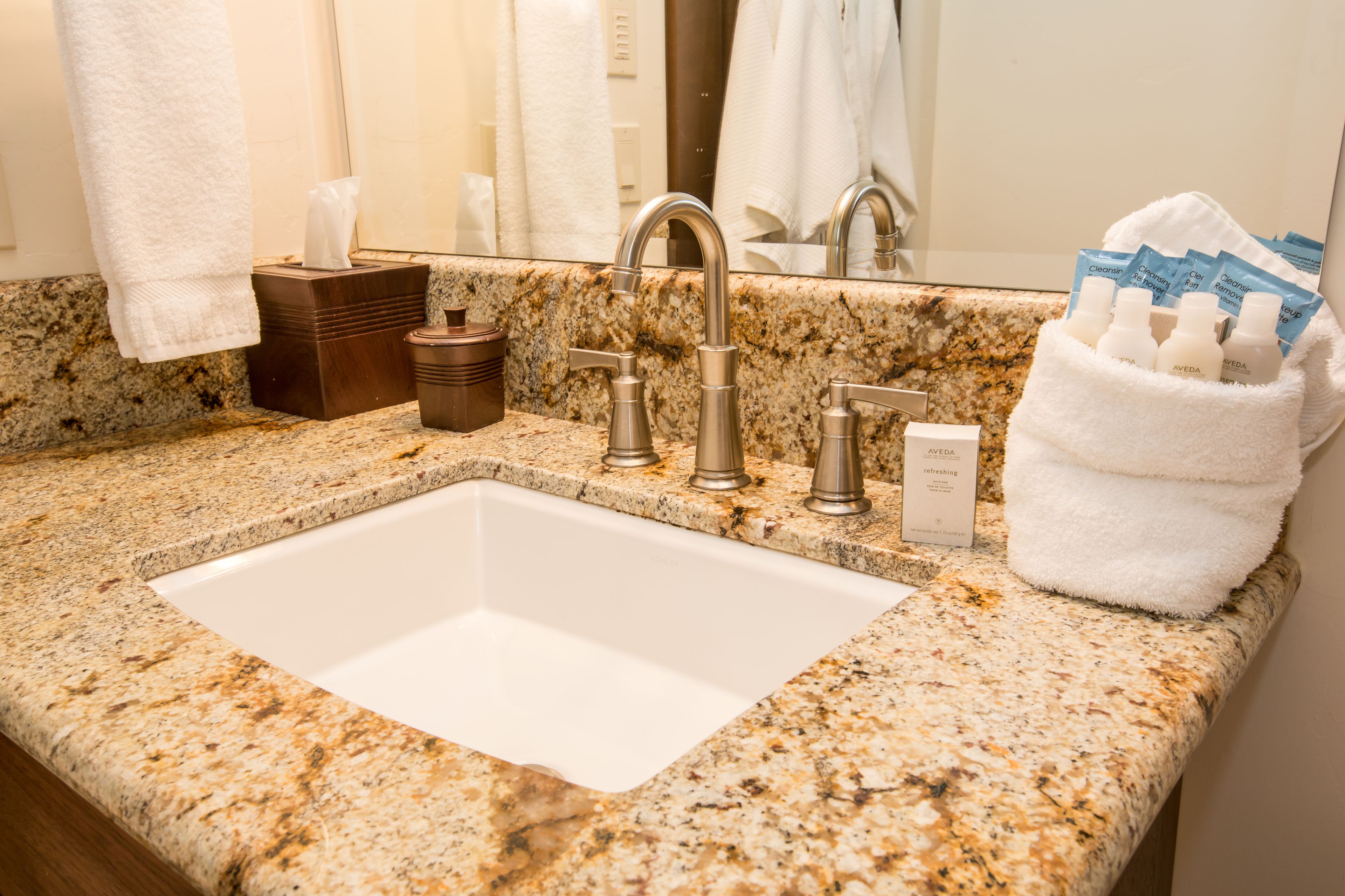 A bathroom with a granite countertop, a white sink, and a towel rack.