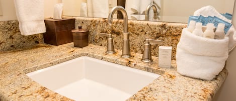 A bathroom with a granite countertop, a white sink, and a towel rack.