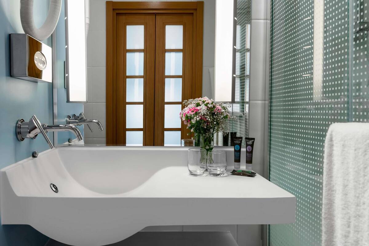 A modern bathroom with a freestanding bathtub, a wooden door, and a glass shower enclosure.