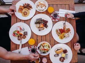 A wooden table with various plates of food, utensils, and glasses of juice. - Novotel Trabzon (Yomra)