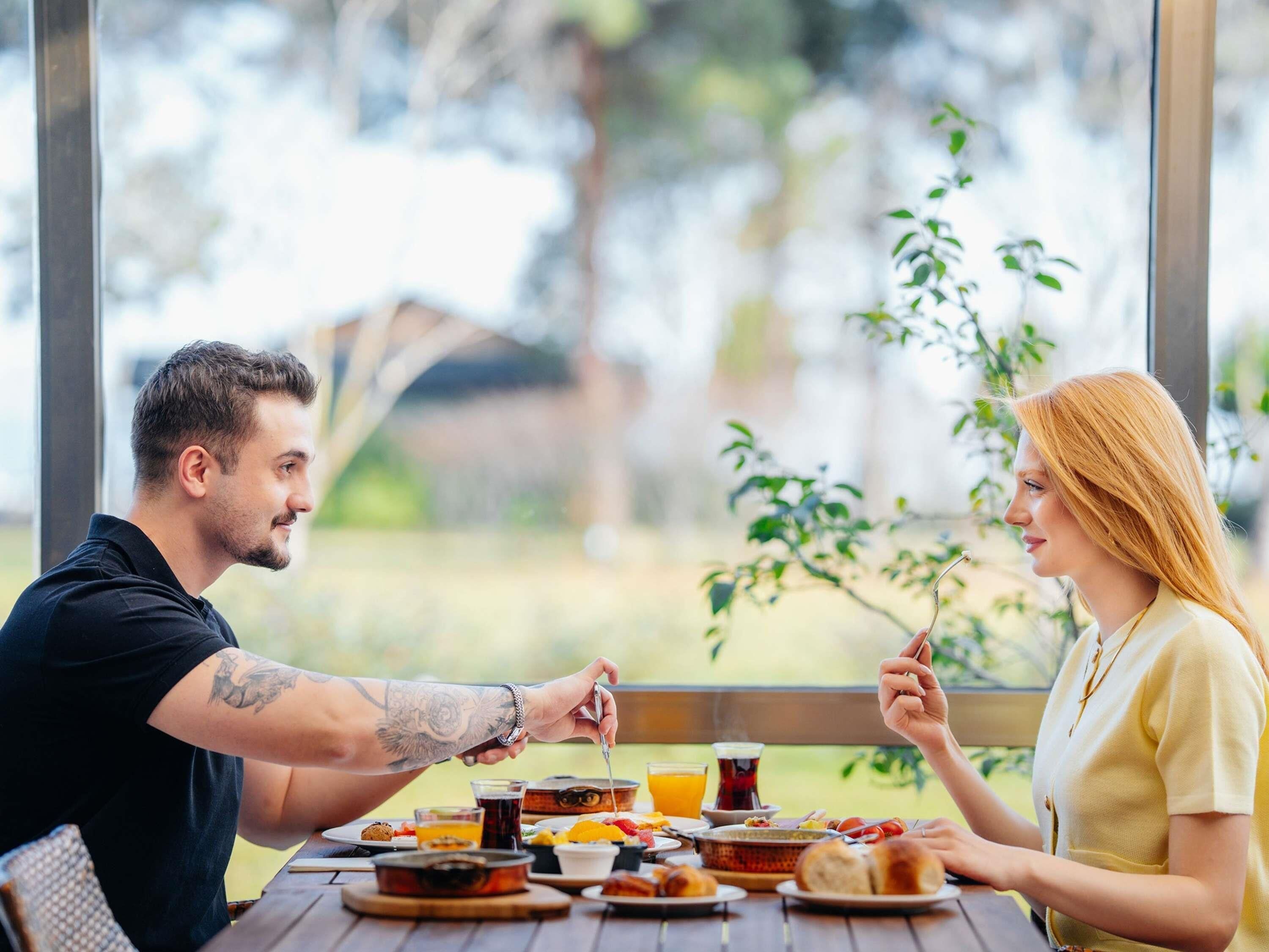 A dining table with various dishes, a glass of orange juice, and a cup of tea.