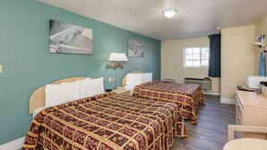Camera d'albergo con due letti, una scrivania, una sedia, una finestra con tende e opere d'arte appese alle pareti.
