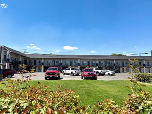 A motel with a parking lot, multiple vehicles, and a clear sky.