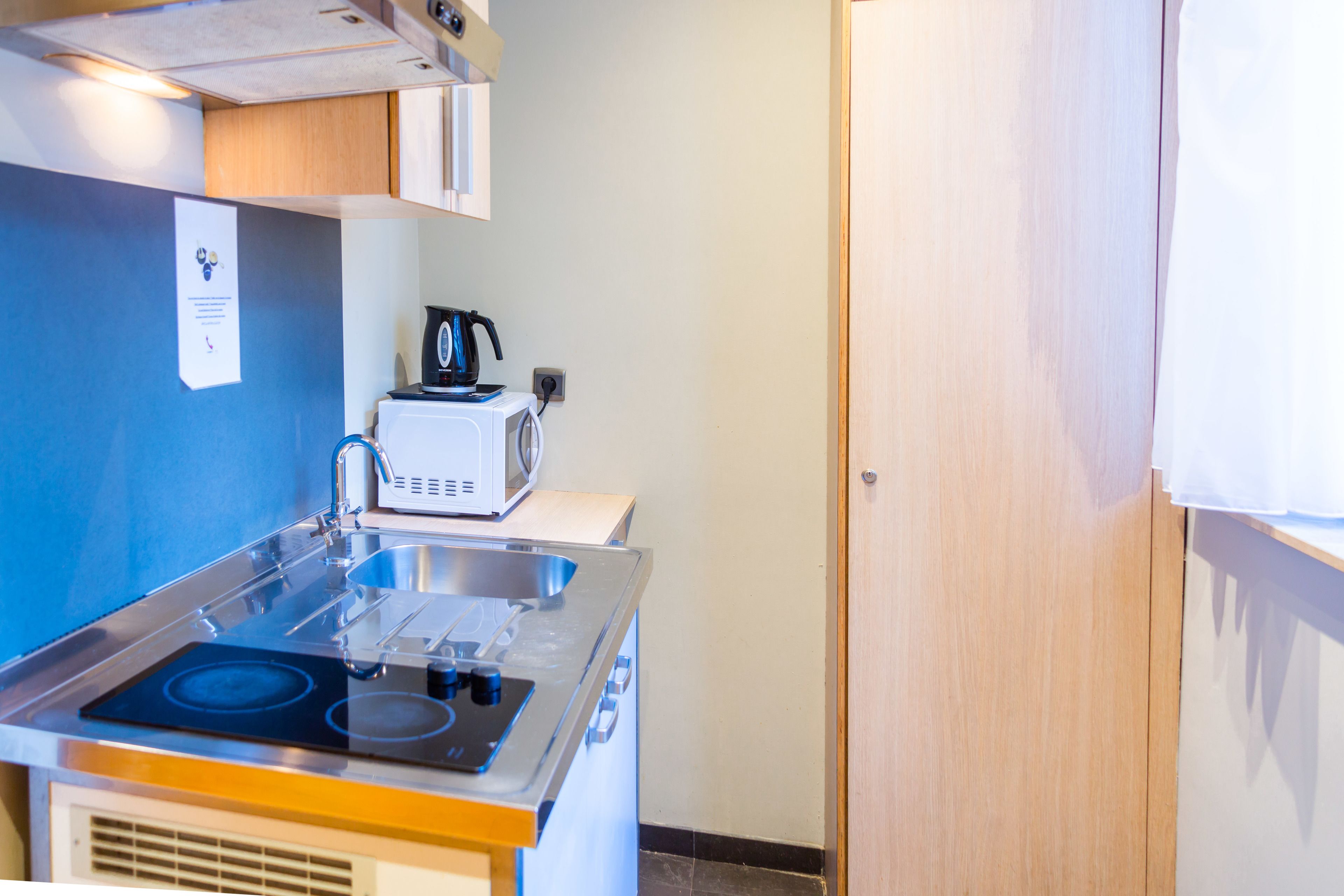 A compact kitchen with a stove, sink, and microwave.