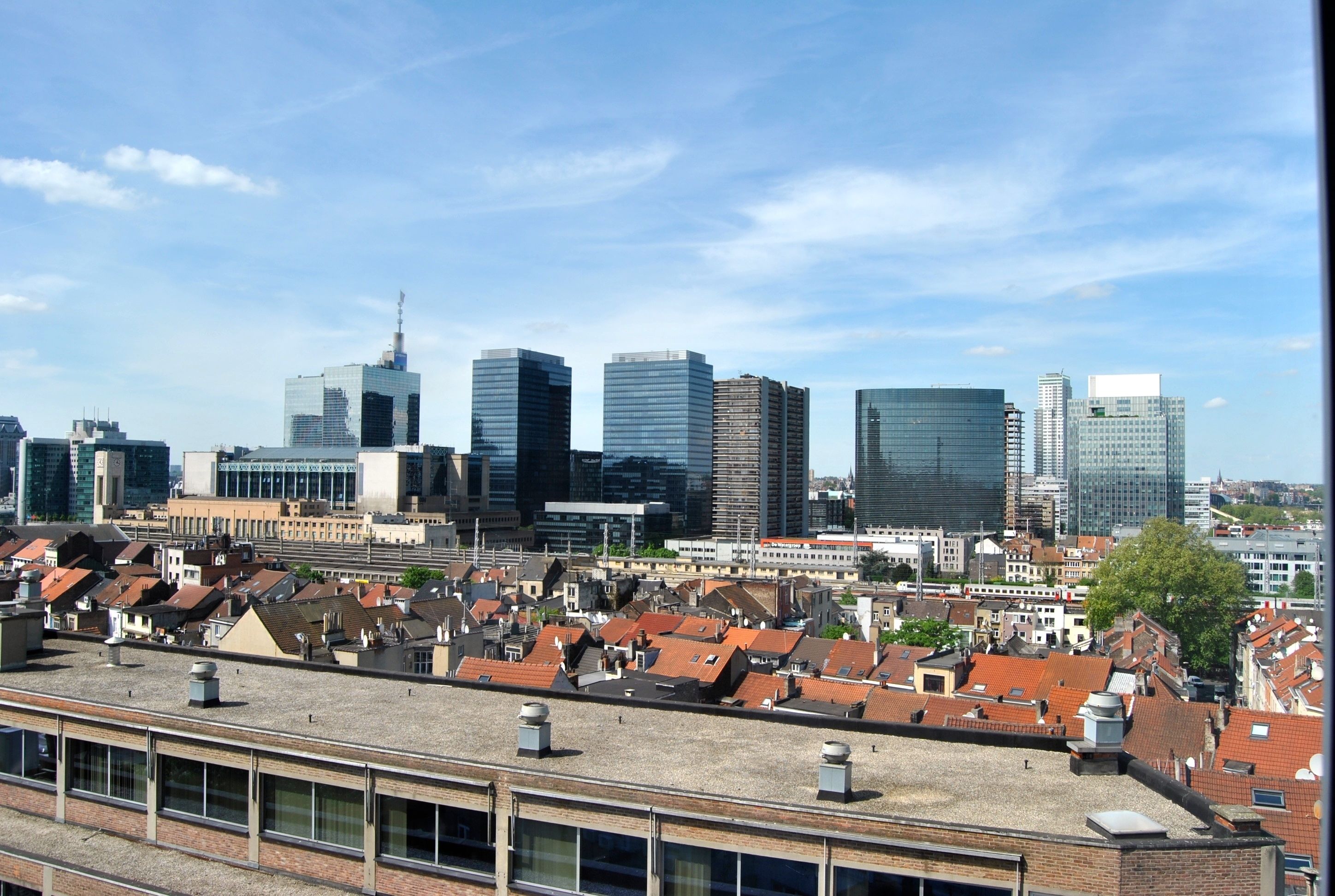 Un paysage urbain comprenant des immeubles modernes de grande hauteur et des bâtiments résidentiels traditionnels de faible hauteur.
