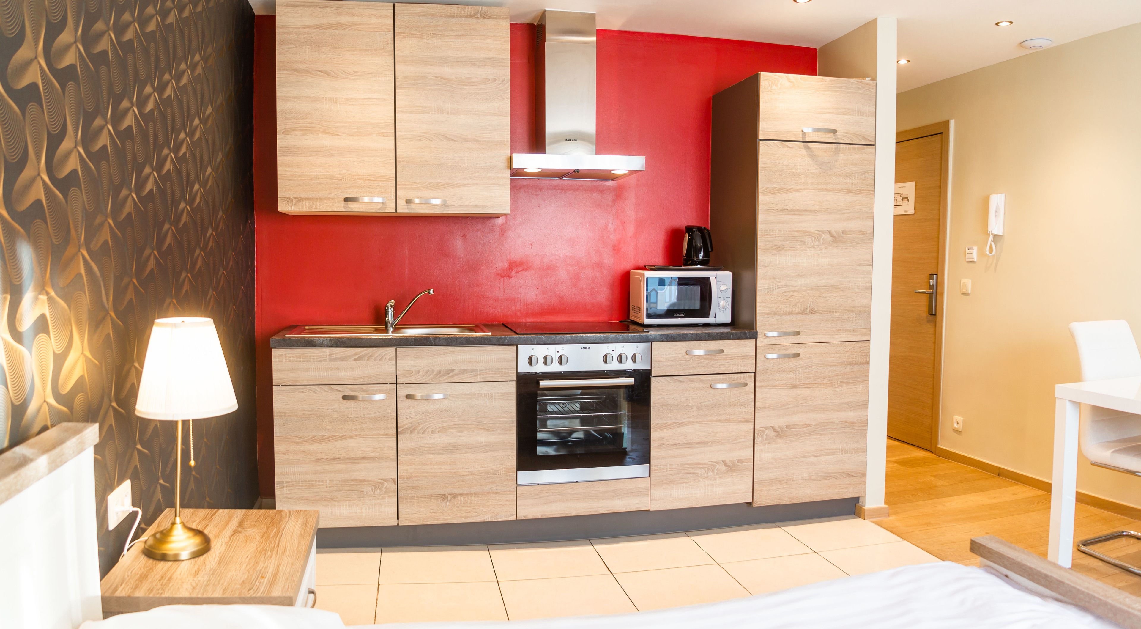 A modern kitchen with wooden cabinets, a built-in oven, and a microwave.