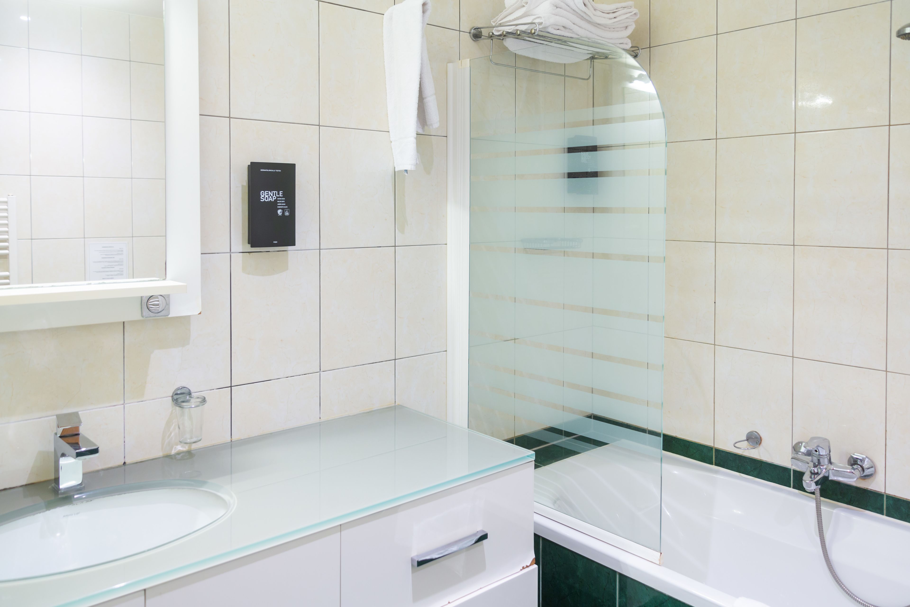 Une salle de bain moderne avec un lavabo à vasque en verre, une douche à parois de verre et une baignoire blanche.
