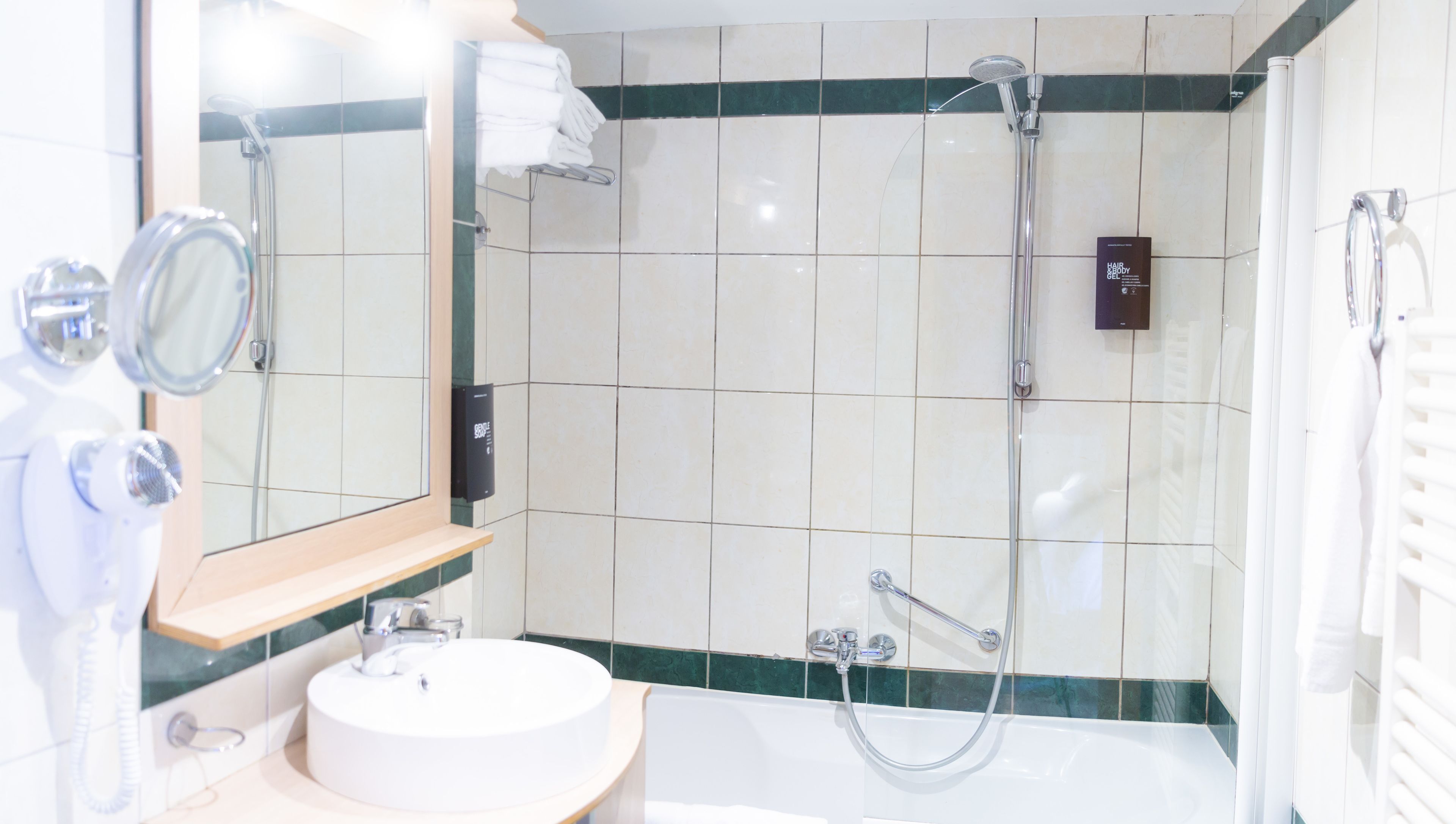 A bathroom with a sink, mirror, and shower.