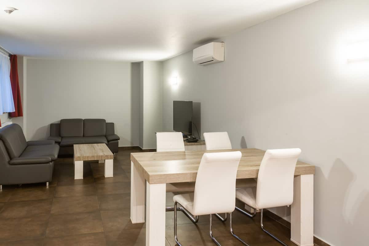 A modern living room with a sofa, a coffee table, and a dining table with chairs.