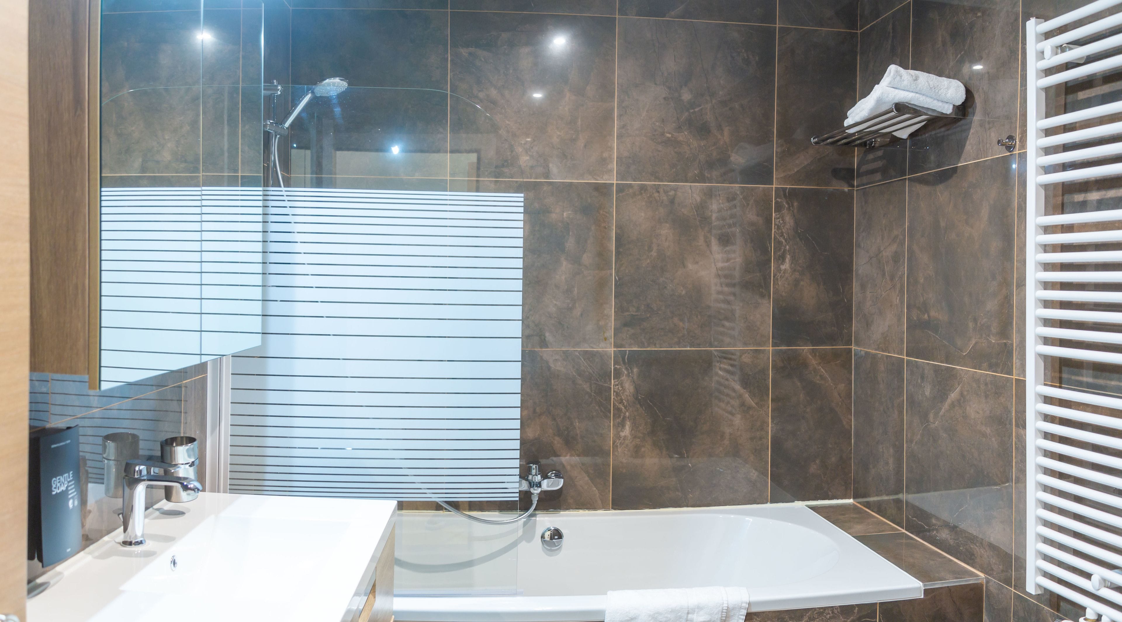 Un baño moderno con una bañera, ducha y un espejo grande.