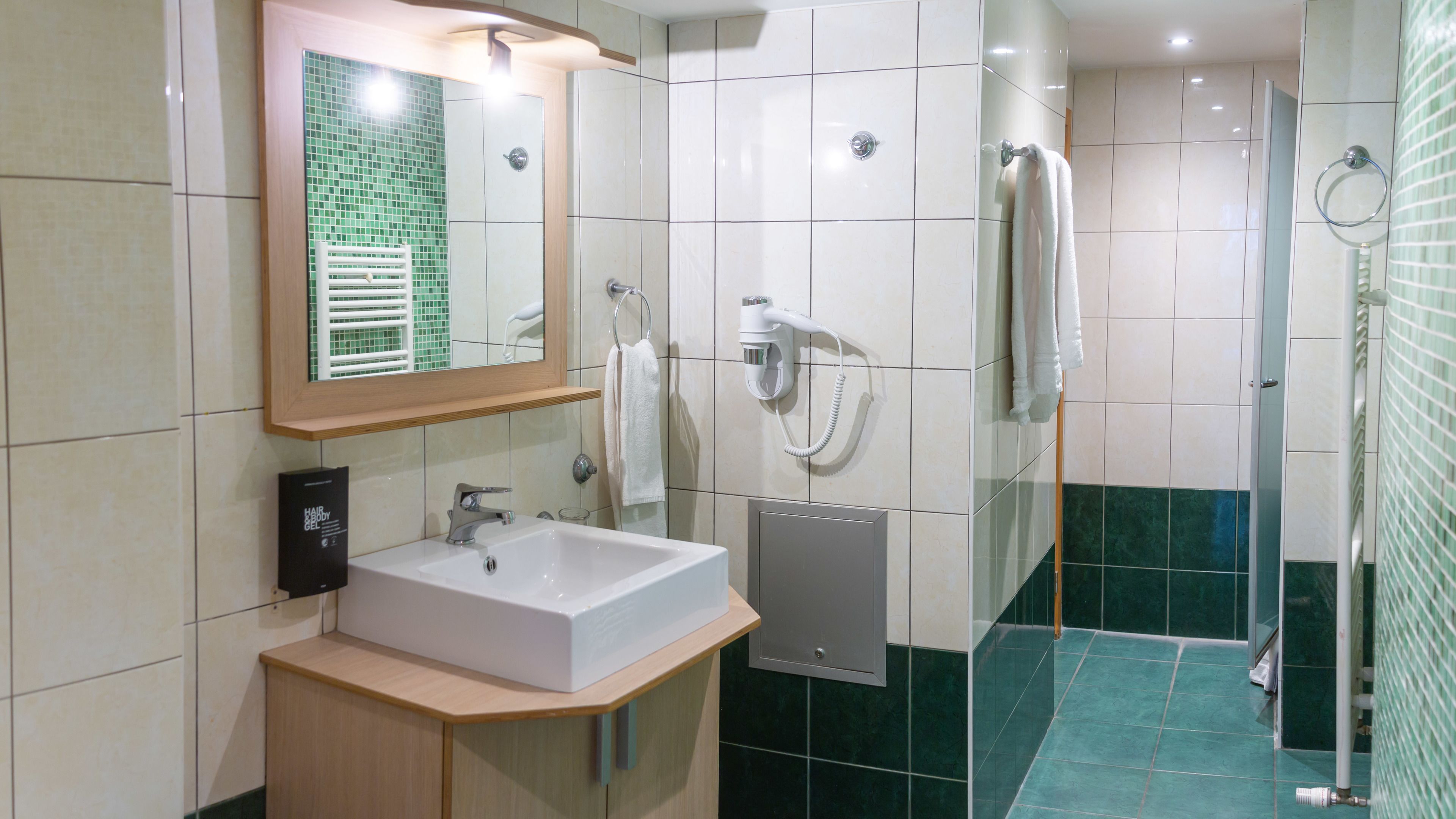 A modern bathroom with a sink, mirror, and a hairdryer mounted on the wall.